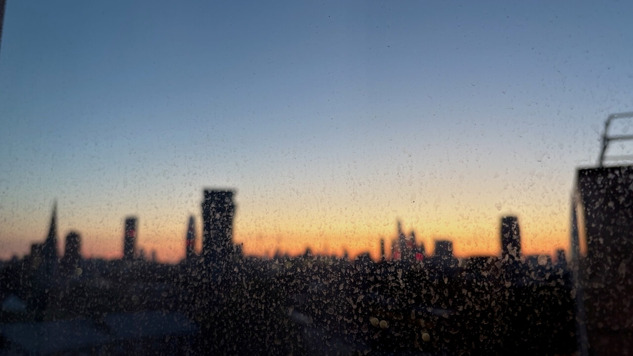 A sunset, rain-soaked skyline showing industrial buildings.